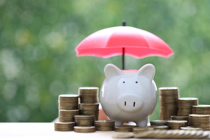 Photo of a piggy bank and coins with pink umbrella